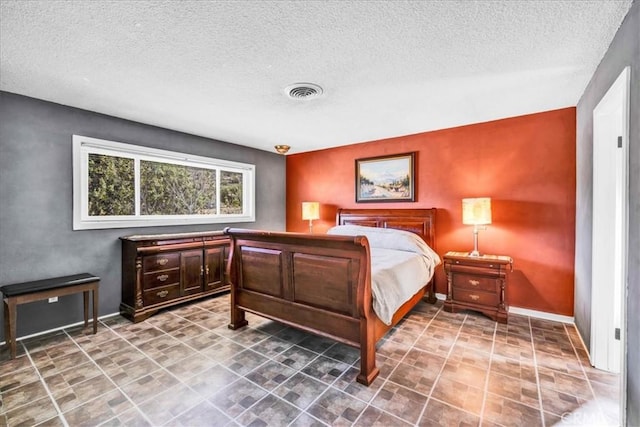 bedroom featuring visible vents, baseboards, and a textured ceiling