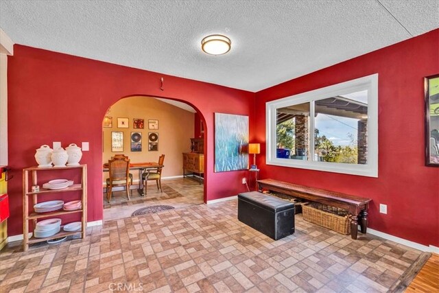 interior space featuring baseboards, arched walkways, and a textured ceiling