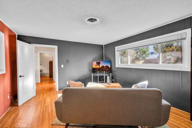 living room with visible vents, light wood-style floors, and a textured ceiling