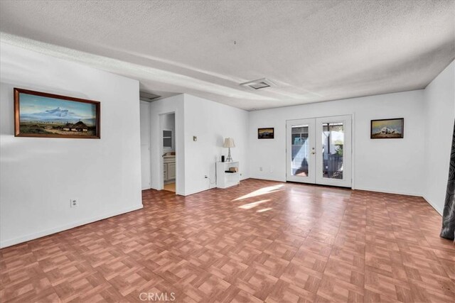 spare room with visible vents, french doors, a textured ceiling, and baseboards