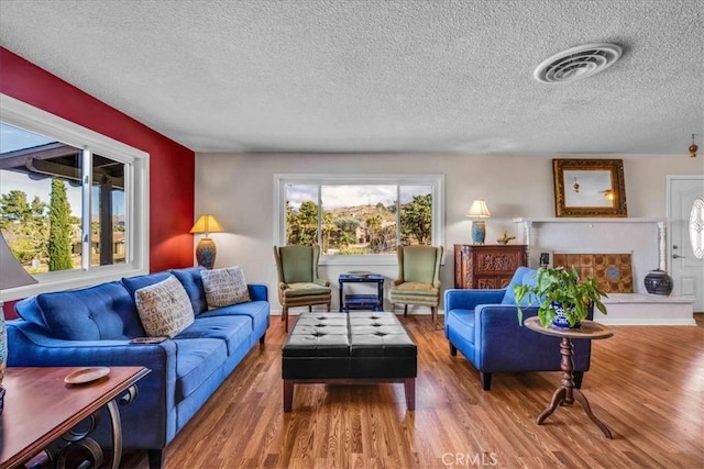 living area with a wealth of natural light, visible vents, and wood finished floors