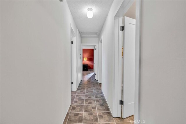 corridor with attic access and a textured ceiling