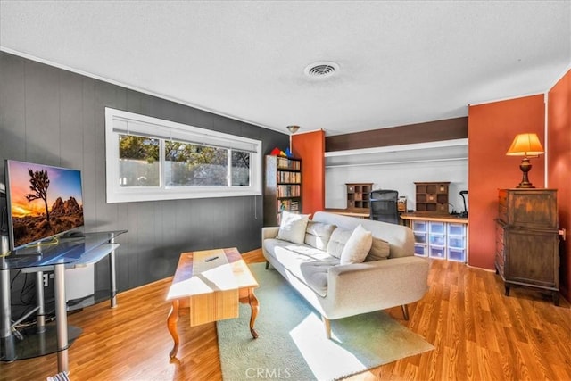 living area with visible vents, a textured ceiling, and wood finished floors