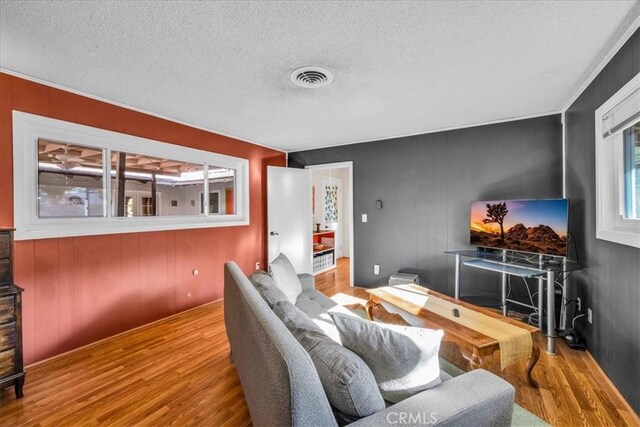 living room featuring visible vents, a textured ceiling, and wood finished floors