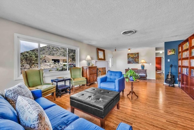 living area with wood finished floors, visible vents, and a textured ceiling