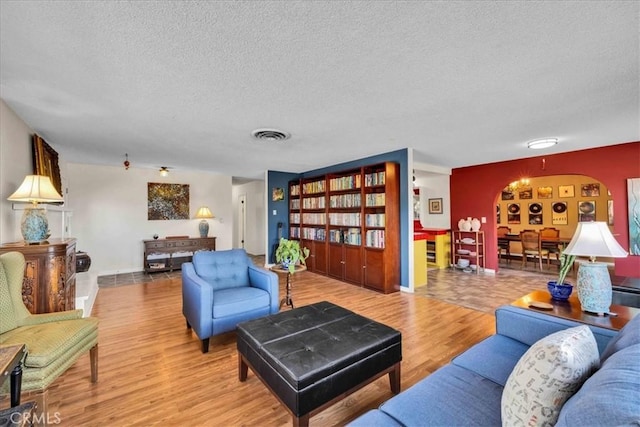 living room with visible vents, a textured ceiling, and wood finished floors