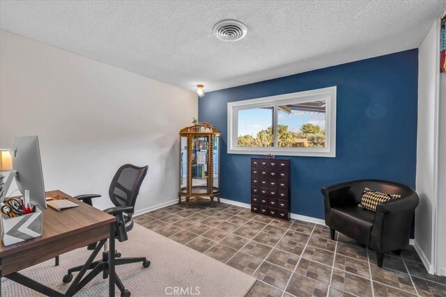 office space with baseboards, visible vents, and a textured ceiling