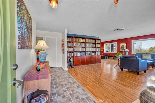 sitting room with visible vents, a textured ceiling, and wood finished floors