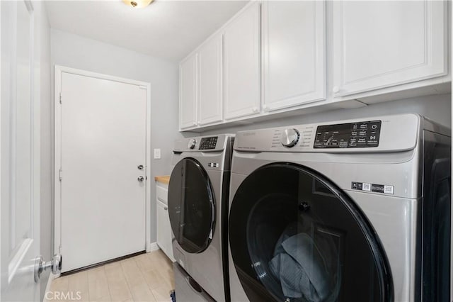 laundry room with washing machine and dryer and cabinets