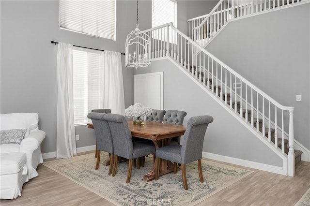 dining area featuring a high ceiling, hardwood / wood-style flooring, and a chandelier