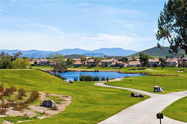 view of home's community with a water and mountain view and a yard