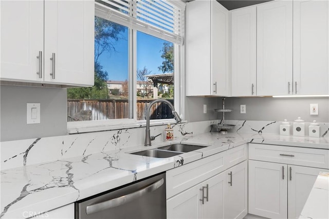 kitchen with white cabinets, stainless steel dishwasher, light stone countertops, and sink