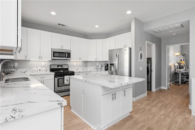 kitchen with stainless steel appliances, a center island, sink, and white cabinetry