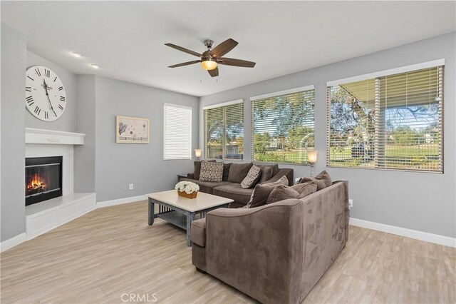 living room with ceiling fan, light wood-type flooring, and a wealth of natural light