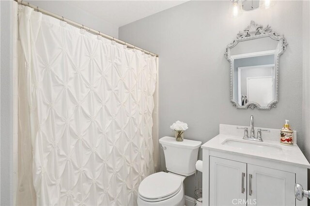 bathroom with toilet, a shower with shower curtain, and vanity