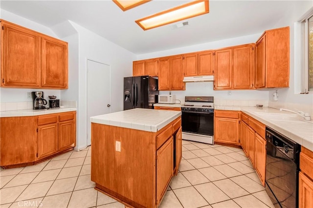 kitchen with tile countertops, a kitchen island, black appliances, sink, and light tile patterned floors