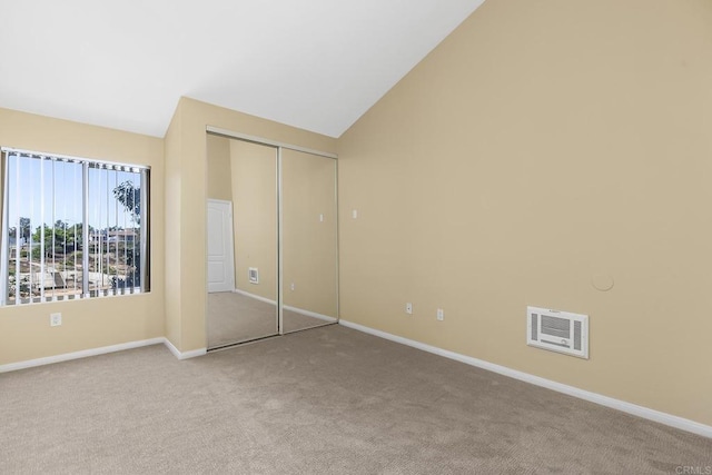 unfurnished bedroom with light colored carpet, high vaulted ceiling, and a closet