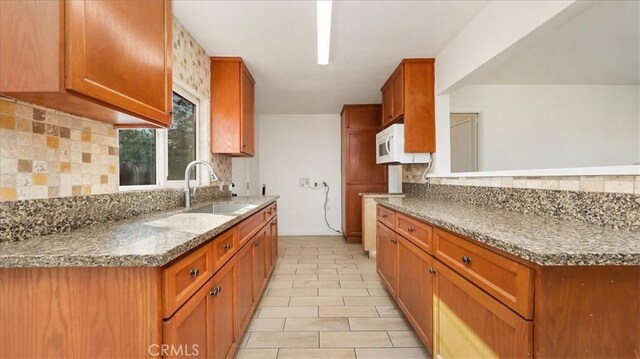 kitchen featuring decorative backsplash, light stone counters, and sink