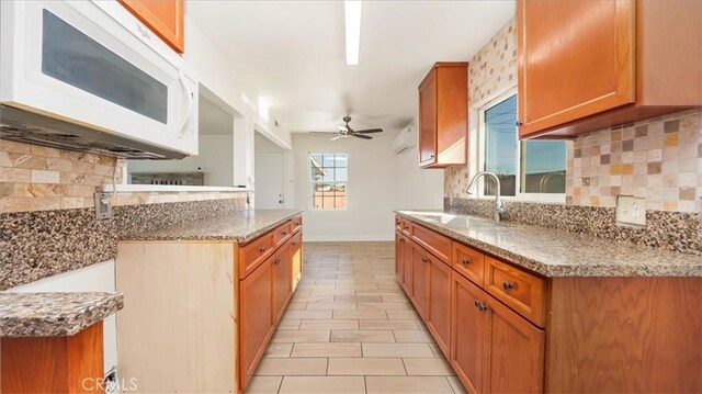 kitchen with ceiling fan, sink, an AC wall unit, and backsplash