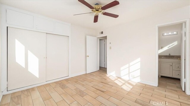 unfurnished bedroom with ceiling fan, light wood-type flooring, connected bathroom, and a closet