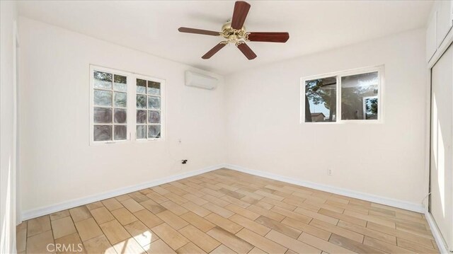 spare room featuring ceiling fan, light wood-type flooring, and a wall mounted AC