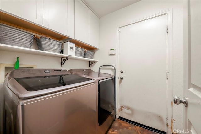 laundry area featuring dark tile patterned floors, separate washer and dryer, and cabinets