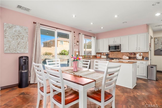 kitchen featuring white cabinets, backsplash, sink, and a center island