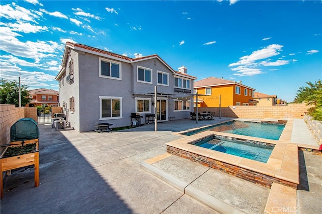 back of house featuring an in ground hot tub and a patio area