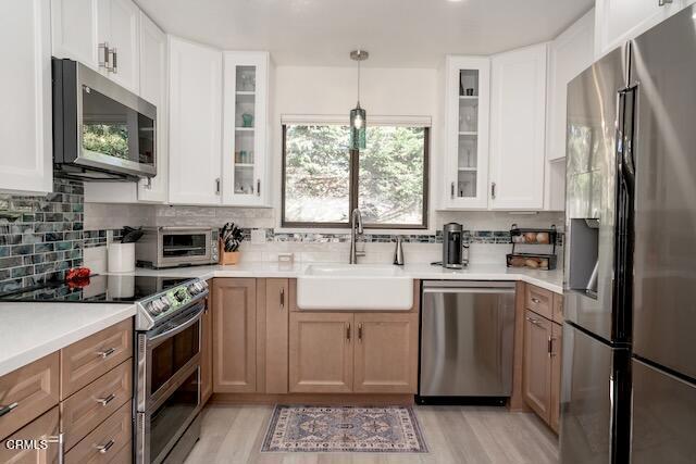 kitchen with pendant lighting, stainless steel appliances, sink, and white cabinets