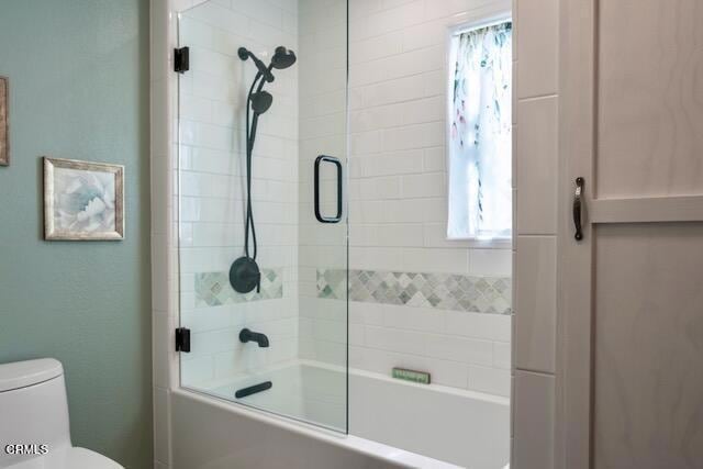 bathroom featuring shower / bath combination with glass door and toilet