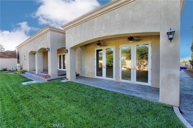 back of property with a lawn, ceiling fan, french doors, and a patio