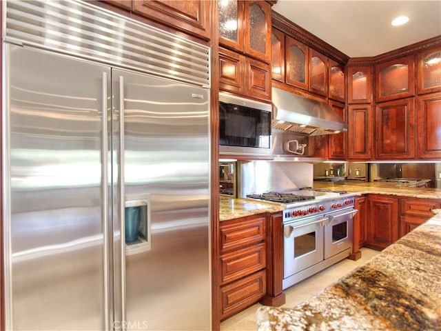 kitchen with built in appliances, light stone counters, and light tile patterned floors