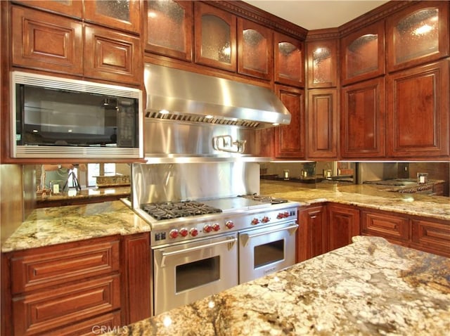 kitchen with high end stainless steel range oven, light stone counters, and black microwave