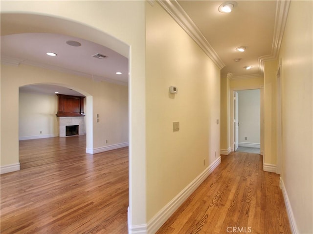 corridor with light hardwood / wood-style floors and crown molding