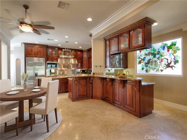 kitchen featuring built in appliances, decorative light fixtures, ceiling fan, and crown molding