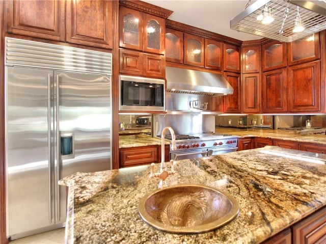 kitchen with built in appliances, light stone counters, and hanging light fixtures