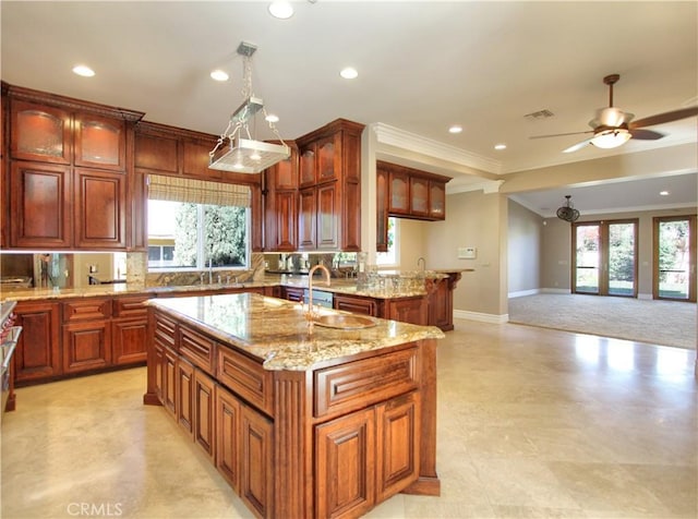 kitchen with a center island with sink, ceiling fan, a healthy amount of sunlight, and pendant lighting