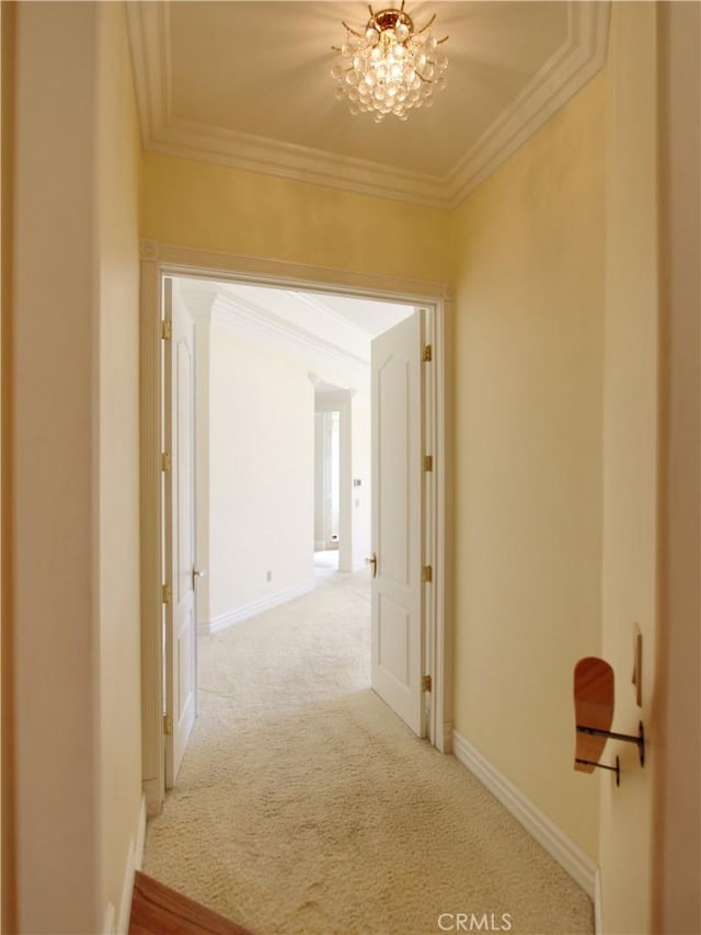 hall featuring crown molding, carpet floors, and an inviting chandelier