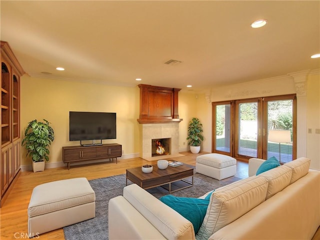 living room with a fireplace, light wood-type flooring, and ornamental molding