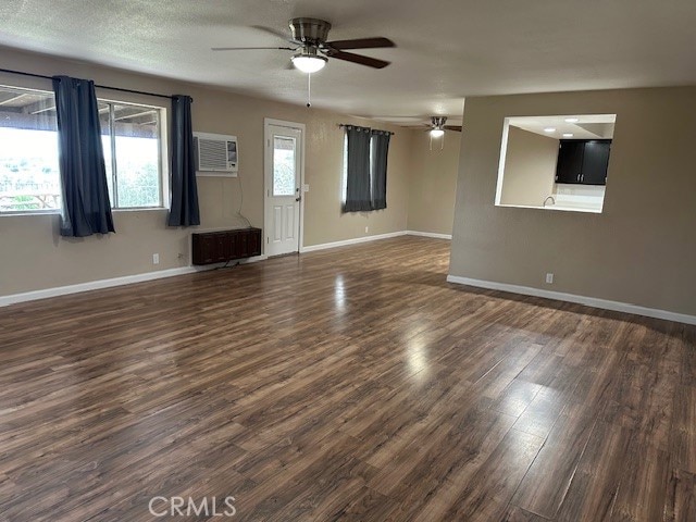 interior space with ceiling fan, radiator, a wall mounted AC, a textured ceiling, and dark wood-type flooring