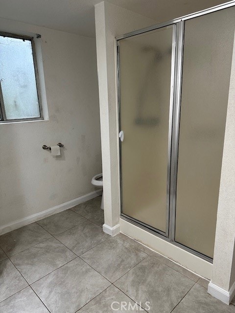 bathroom with tile patterned floors, an enclosed shower, and toilet