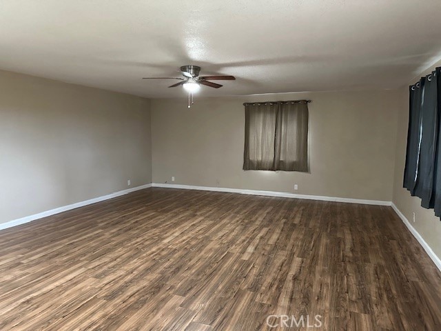 spare room featuring ceiling fan and dark wood-type flooring