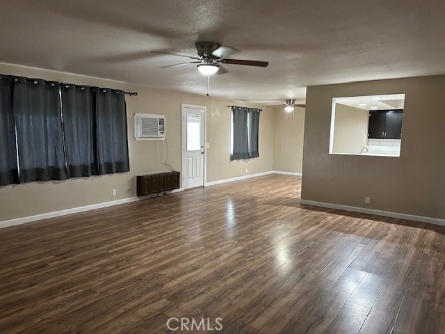 unfurnished living room with ceiling fan, dark hardwood / wood-style floors, radiator heating unit, and an AC wall unit