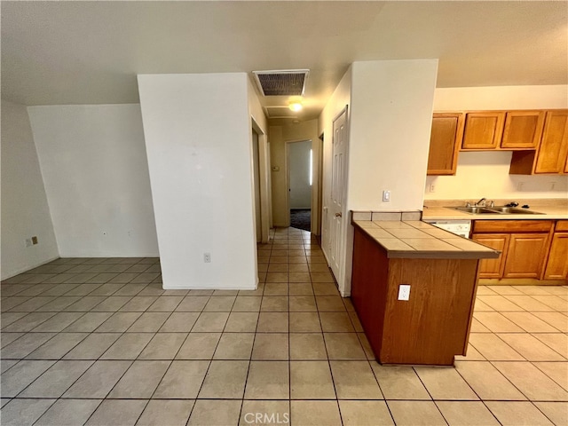 kitchen featuring light tile patterned flooring, kitchen peninsula, and sink