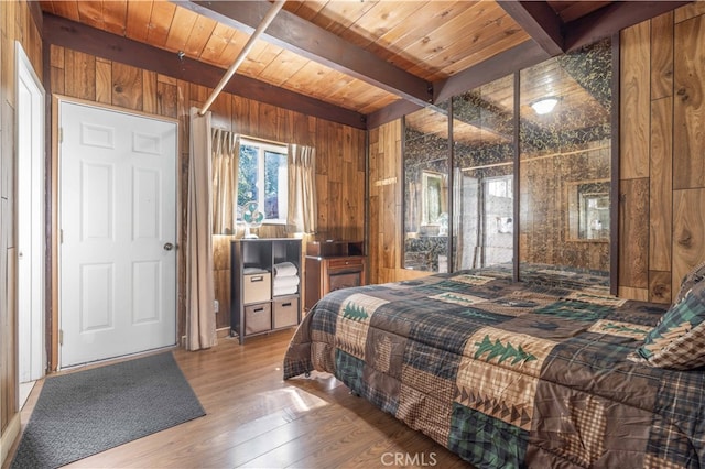 bedroom featuring hardwood / wood-style flooring, wooden walls, beam ceiling, and wooden ceiling