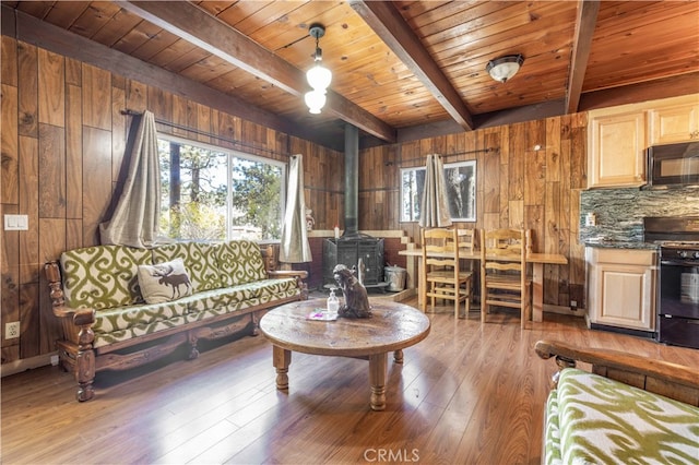 living room with hardwood / wood-style floors, wood ceiling, a wood stove, beam ceiling, and wood walls