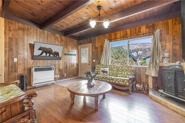 living room with beamed ceiling, wood ceiling, wood walls, wood-type flooring, and heating unit