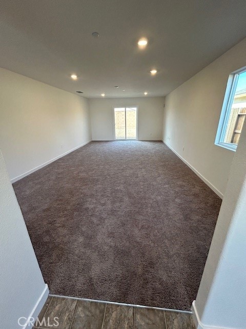 unfurnished room featuring dark colored carpet