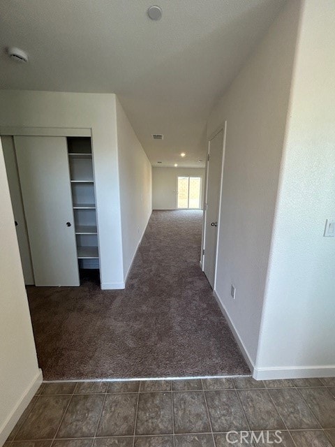 hall with dark colored carpet