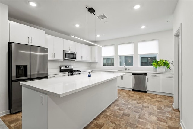 kitchen featuring a center island, stainless steel appliances, white cabinetry, and sink